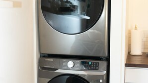 A compact, stainless steel wall-mounted washer and dryer unit with a digital control panel.