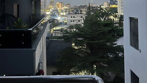 A residential building with a balcony, surrounded by other buildings and trees. - Hibernate - 2 Bedroom Apartment - VI (Lagos)