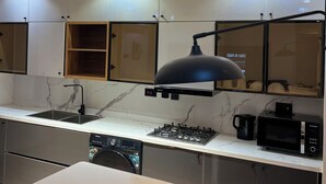 A modern kitchen with a marble countertop, a built-in stove, a coffee maker, and a dishwasher. - Hibernate - 2 Bedroom Apartment - VI (Lagos)