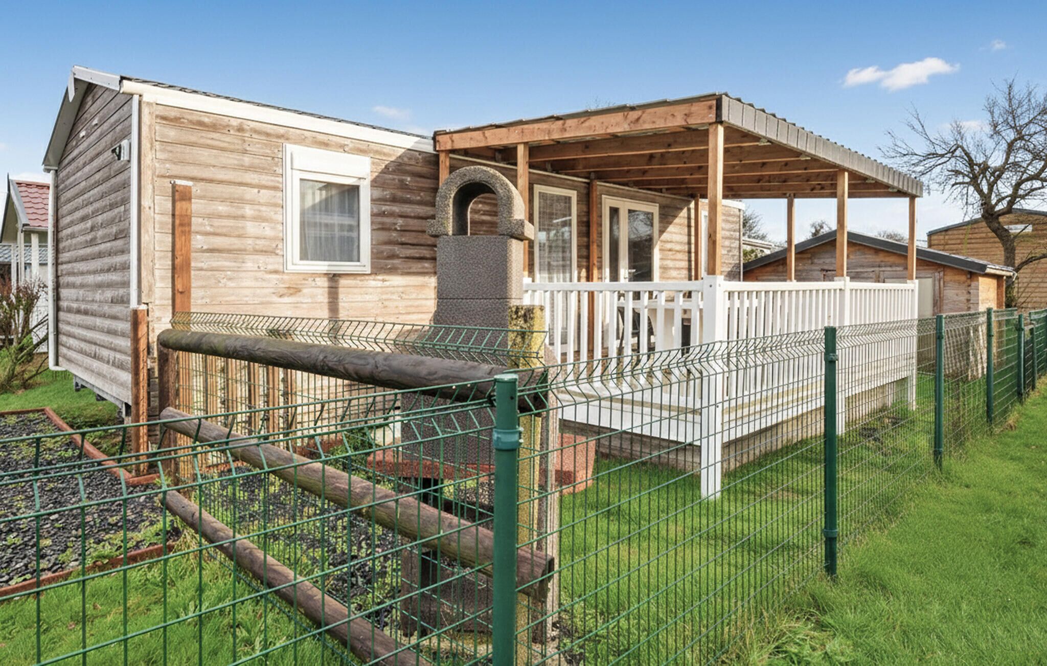 Une cabane en bois avec une véranda et une cour clôturée.