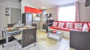 Een knus woongedeelte met een eethoek, kitchenette en een bank met gestreepte kussens.