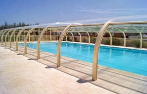 Ein Schwimmbad mit Glasveranda und Fliesenplattform.