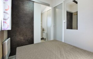 A bedroom with a bed, a radiator, a dark wall, and a mirror. - Mobile-home proche mer 400m (Grandcamp-Maisy)