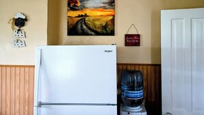 Uma cozinha com geladeira, bebedouro e um quadro na parede.