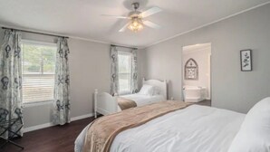 Ein Schlafzimmer mit zwei Betten, einem Deckenventilator und einem Fenster mit Vorhängen.