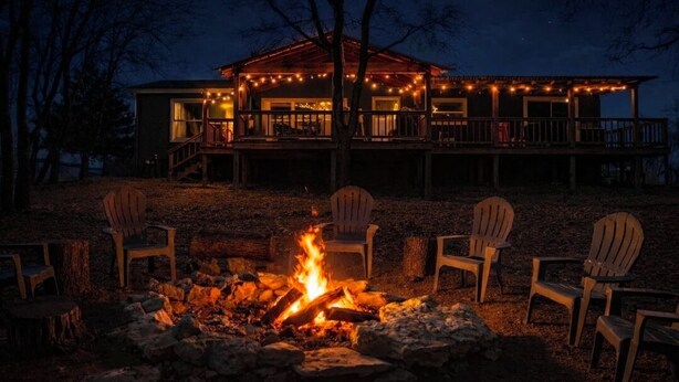 Eine Lodge mit Feuerstelle und Sitzgelegenheiten im Freien, umgeben von Bäumen.