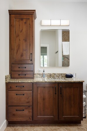 A bathroom with a wooden vanity, a sink, a mirror, and a towel rack. - Lakefront Cottage on Lake Leelanau | Dock, Fire Pit, Near M-22 & Dunes (Lake Leelanau)