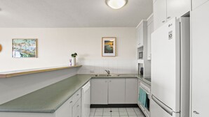 Una cocina moderna con armarios blancos, encimera verde, un fregadero y un refrigerador.