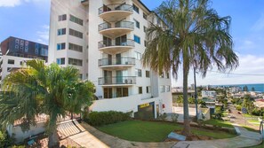 A multi-story residential building with balconies, a well-maintained lawn, and a view of the sea. - Highpoint Unit 2, 35 Maltman Street, Kings Beach (Kings Beach)