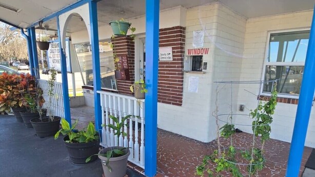 A building with a covered porch, potted plants, and a sign indicating a security office. - Holiday Motel Ocala Downtown I-75 (Ocala)
