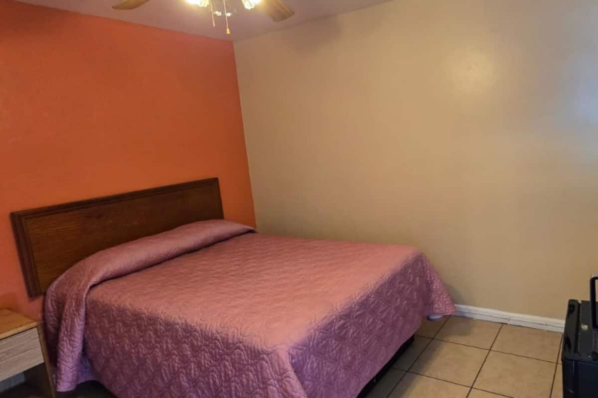 A single bed with a wooden headboard in a room with orange and beige walls.