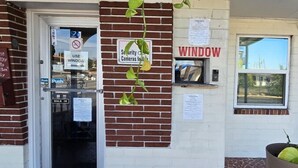A building entrance with a security camera sign, a window, and a door. - Holiday Motel Ocala Downtown I-75 (Ocala)