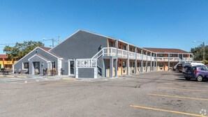 A motel with a grey building and a yellow building with balconies. There are cars parked in the lot. - Siesta Motor Inn Kissimmee Near Disney World (Kissimmee)