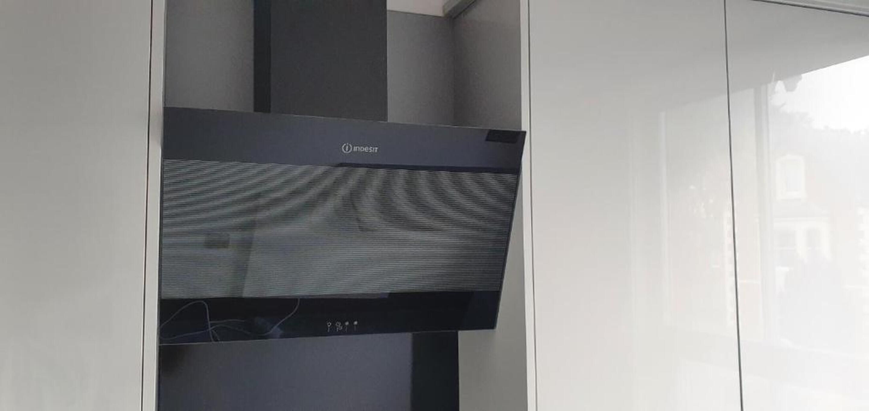 A modern kitchen with a built-in induction cooktop and a stainless steel range hood.