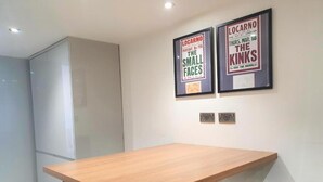 A modern kitchen with a wooden table and black chairs. There are two framed posters on the wall. - Oyo Studio @74 (Swindon)
