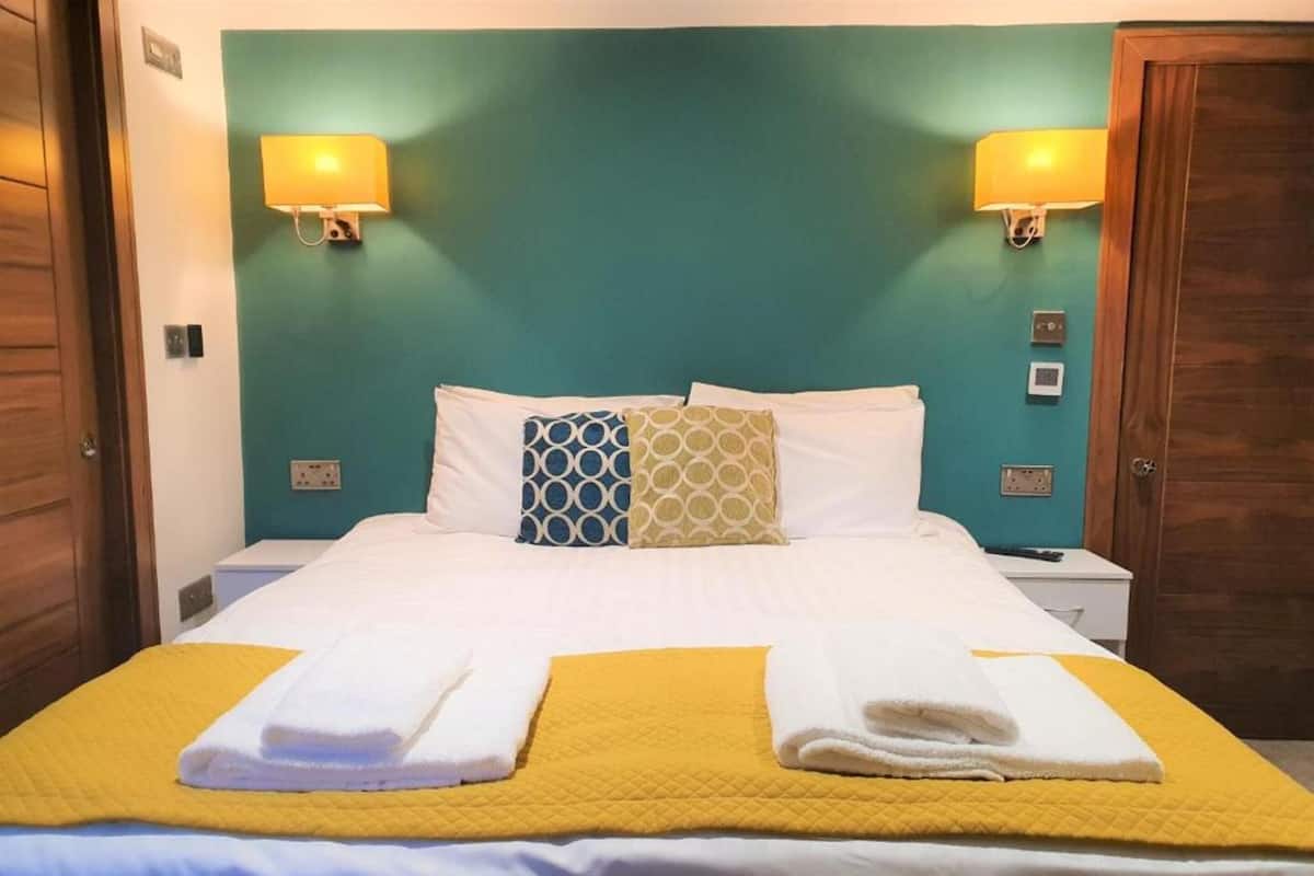 Een hotelkamer met een bed, twee bedlampen, een deur en een stopcontact.