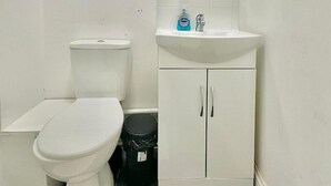 A small, white bathroom with a toilet, a sink, and a cabinet. - 10-minute Ride to Central London A (London)