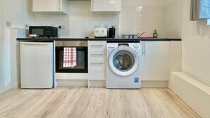 A compact kitchen with a microwave, toaster, and washing machine. - 10-minute Ride to Central London A (London)