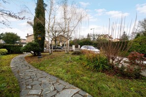 A stone pathway leading to a residential area with houses, a lamp post, and a car parked nearby. - Maison Le Reflet de Marne - Welkeys (Vaires-sur-Marne)