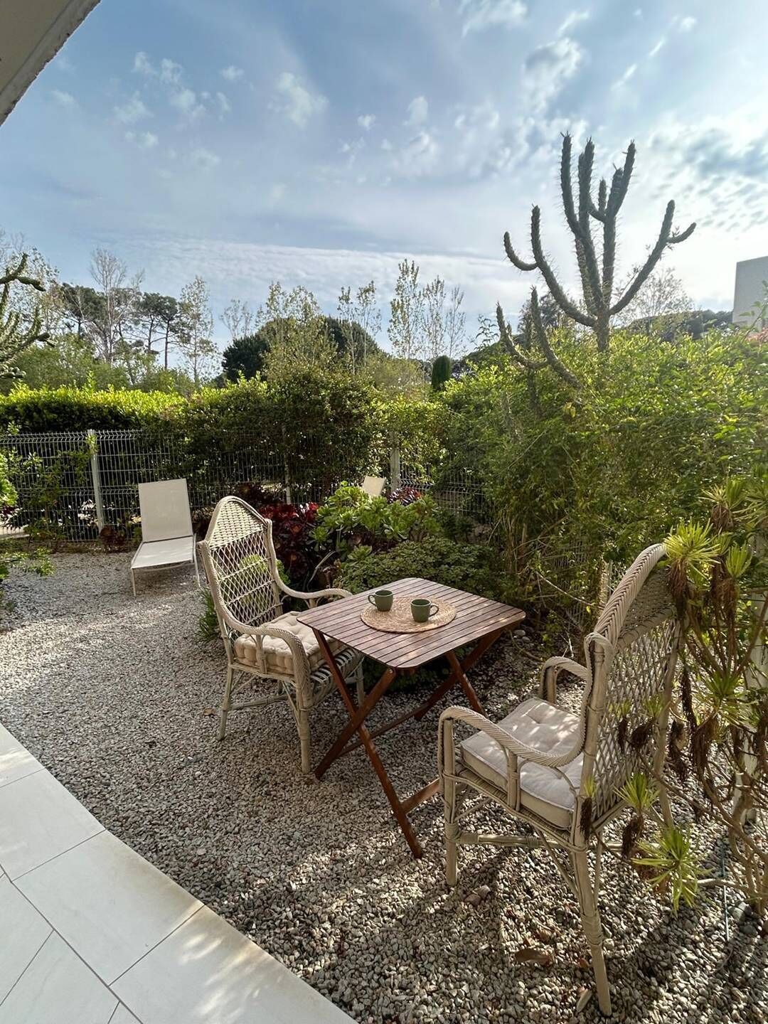 Eine Terrassengaststätte mit Korbmöbeln, einem Tisch und Blick auf eine Wüstenlandschaft.