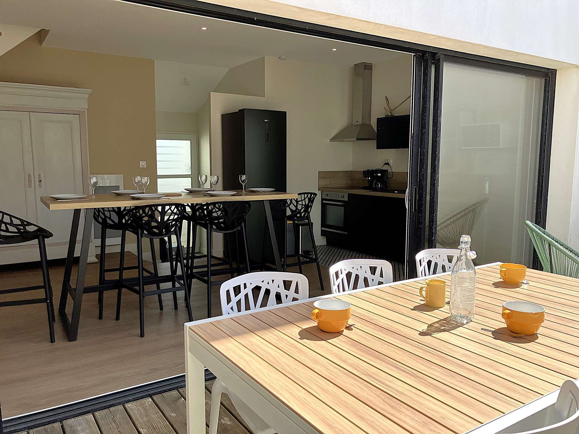 Ein Essbereich mit Holztisch, weißen Stühlen und einer Küche im Hintergrund.