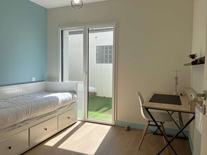 A bedroom with a bed, a desk, and a chair, a sliding glass door to a balcony, and a small potted plant on the wall. - Le Château de Sab - Saint Hilaire de Riez (SAINT HILAIRE DE RIEZ)