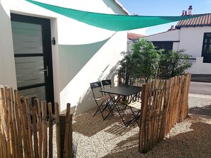 A patio with a table and chairs, a bamboo fence, and a green shade sail. - Le Château de Sab - Saint Hilaire de Riez (SAINT HILAIRE DE RIEZ)