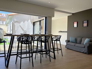 A modern dining area with a table and chairs, a sofa, and a view of the outside. - Le Château de Sab - Saint Hilaire de Riez (SAINT HILAIRE DE RIEZ)
