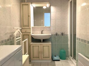 Een badkamer met een wastafel, spiegel, kast en douche.