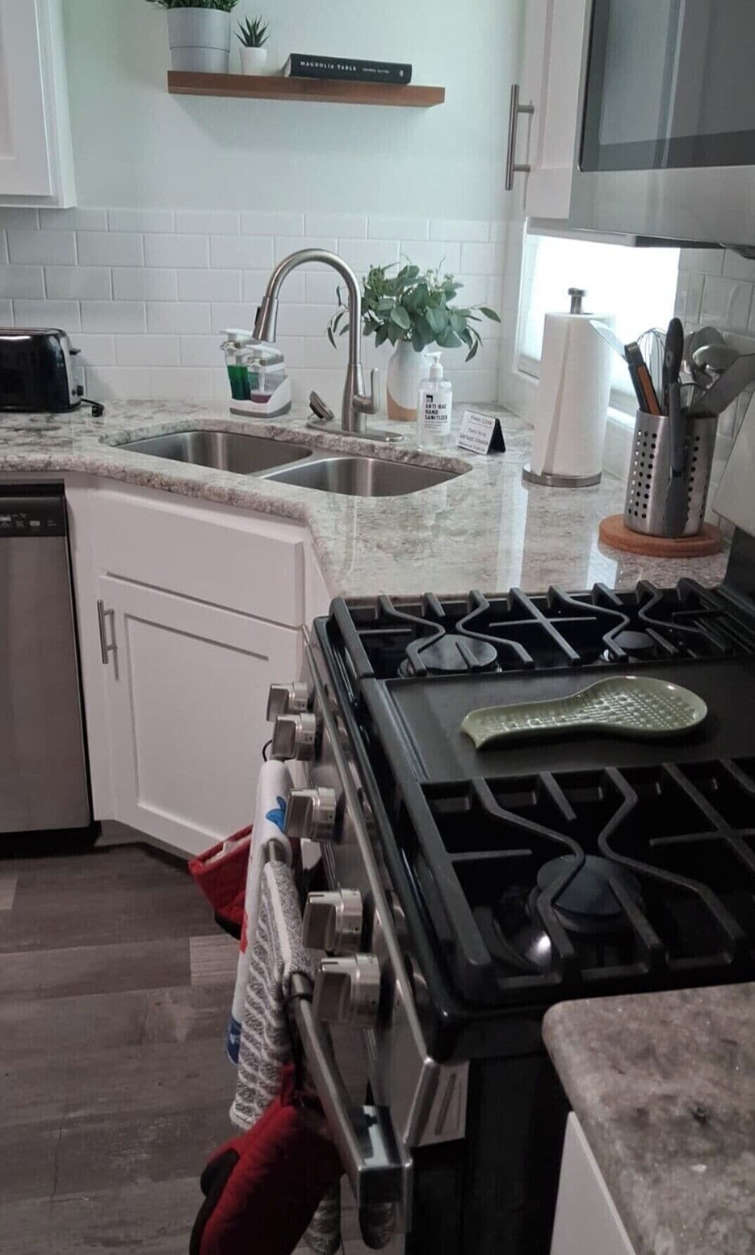 Une cuisine équipée d’une cuisinière, d’un évier et d’un plan de travail.