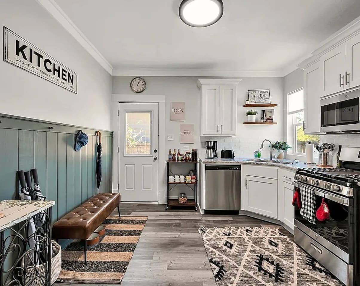 A modern kitchen with white cabinets, a built-in oven, and a coffee station.