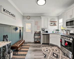 Eine moderne Küche mit weißen Schränken, einem Backofen und einer Kaffeestation.