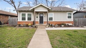 A single-story house with a front porch, a brick foundation, and a small front yard with a pathway leading to the door. - 15 mins to Silos & Baylor | family home w/hot tub + yard (Waco)