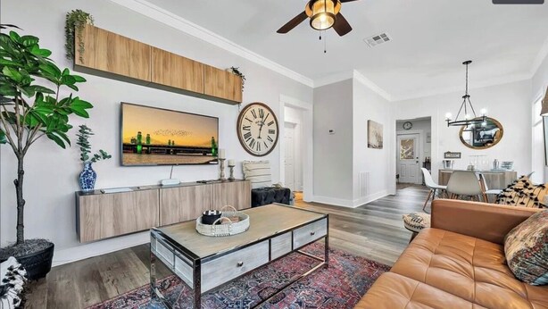 A modern living room with a sofa, coffee table, and a TV mounted on the wall. - 15 mins to Silos & Baylor | family home w/hot tub + yard (Waco)