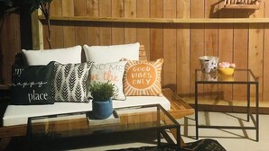 A wooden wall with a sofa and cushions, a small table with a plant, and a lantern. - 15 mins to Silos & Baylor | family home w/hot tub + yard (Waco)