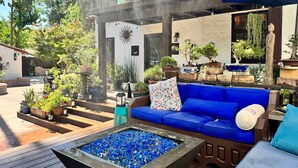 Un patio con un sofá azul, una chimenea y varias macetas con plantas.