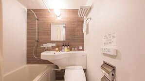 Casa de banho compacta com banheira, sanita e lavatório com artigos de higiene pessoal.
