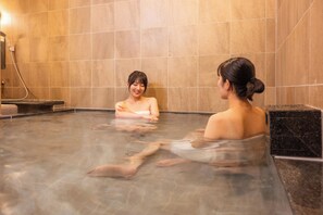Ein Thermalbadbereich mit gefliesten Wänden und Steinboden.