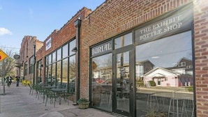 En murbygning med store vinduer og et skilt med teksten "The Exhibit Bottle Shop".