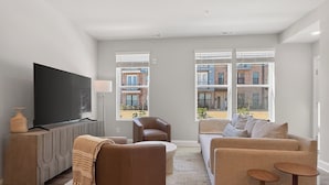 En moderne stue med et fladskærms-tv, en brun sofa, en beige sofa og et sofabord.