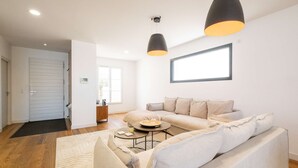 A modern living room with a sofa, coffee table, and pendant lights. - Ovalie - Stunning Family Home with Swimming Pool Just Steps from the Ocean (RIVEDOUX PLAGE)