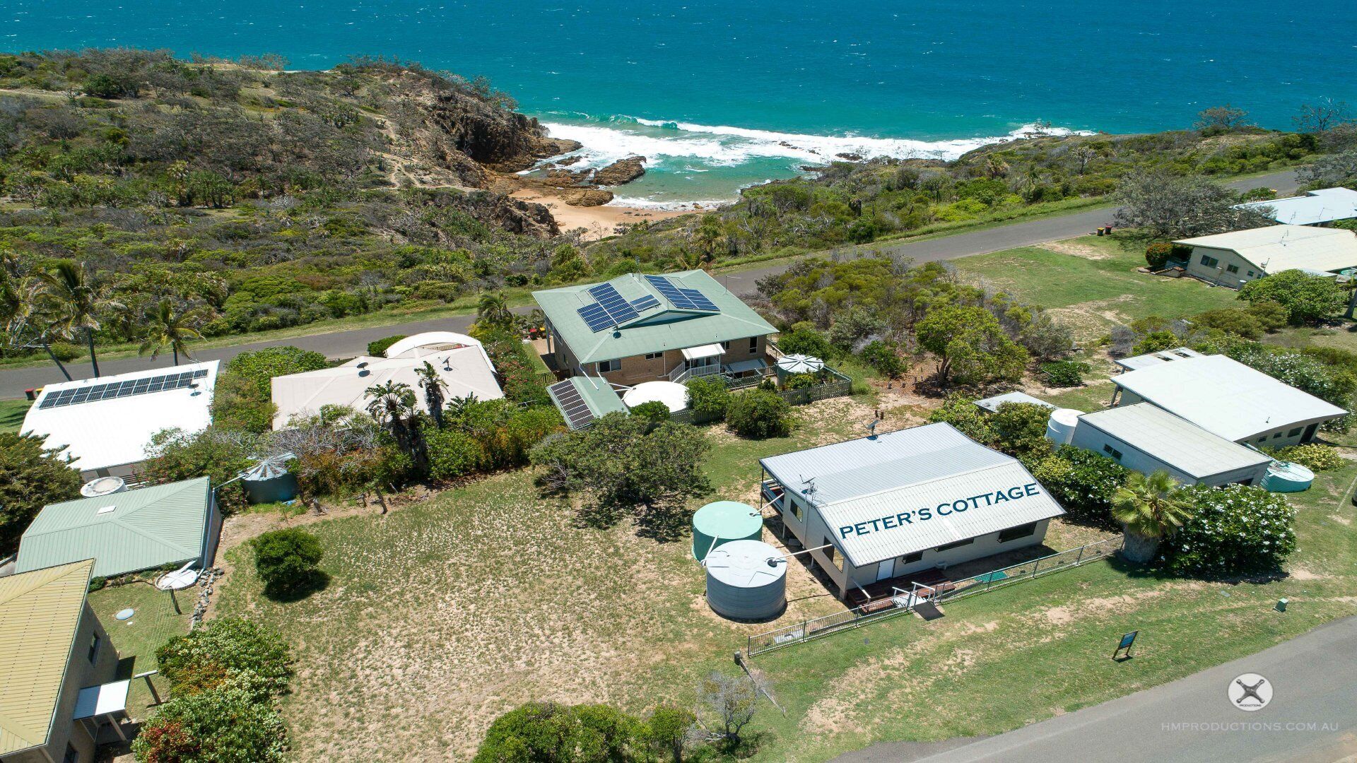 A coastal property with multiple buildings, including a cottage labeled "PETER'S COTTAGE," solar panels, and a large water tank.