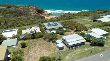 A coastal property with multiple buildings, including a cottage labeled "PETER'S COTTAGE," solar panels, and a large water tank.