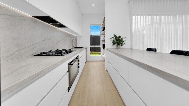 Een moderne keuken met witte kasten, een marmeren aanrechtblad en uitzicht naar buiten.