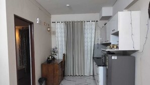 A compact kitchen with a refrigerator, a sink, and a wooden cabinet. - Luxury 1BHK Retreat in Sector 106 - Pool, Gym & Premium Comfort (Gurugram)