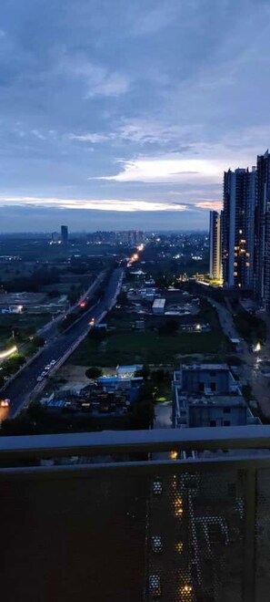 Paisagem urbana ao entardecer, com prédios altos e uma autoestrada.