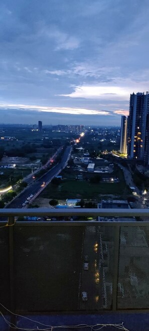 A cityscape at dusk with high-rise buildings, a highway, and a clear sky. - Luxury 1BHK Retreat in Sector 106 - Pool, Gym & Premium Comfort (Gurugram)