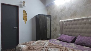 A bedroom with a bed, a wardrobe, and a door. - Luxury 1BHK Retreat in Sector 106 - Pool, Gym & Premium Comfort (Gurugram)