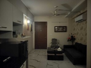 Ein Wohnzimmer mit Sofa, Couchtisch, Fernseher und Deckenventilator.