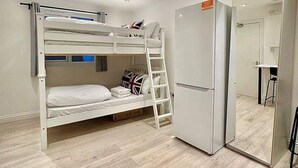 A compact room with a bunk bed, a refrigerator, and a mirror. - Station-side Top-floor Studio (London)